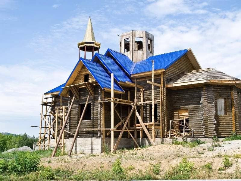 _property-surveyor-church-housing-development-chattanooga-tn 1 | Chattanooga Land Surveying Wooden house under construction with a bright blue metal roof and surrounding scaffolding.